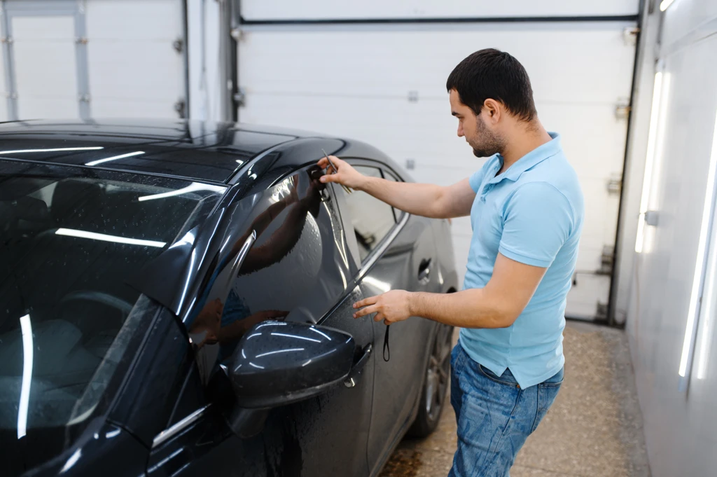 Homme installant une vitre teintée automobile respectant les lois en vigueur au Québec.