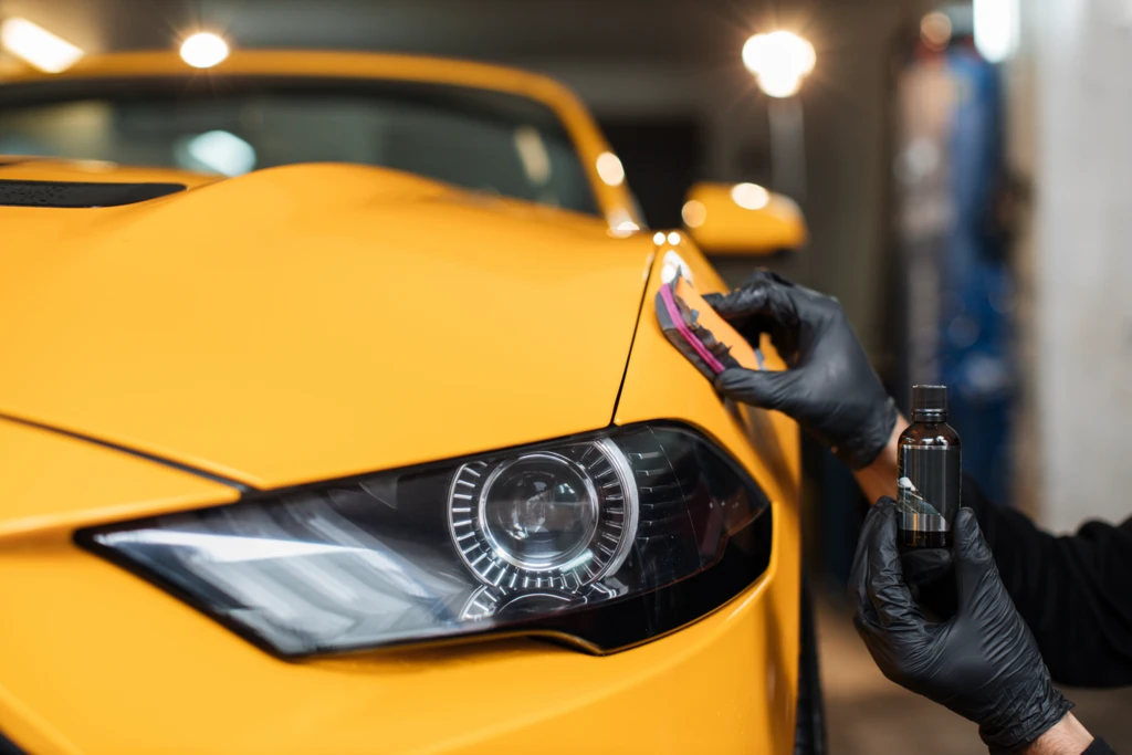 Gros plan de traitement nanocéramique automobile sur une carrosserie au-dessus du phare avant.