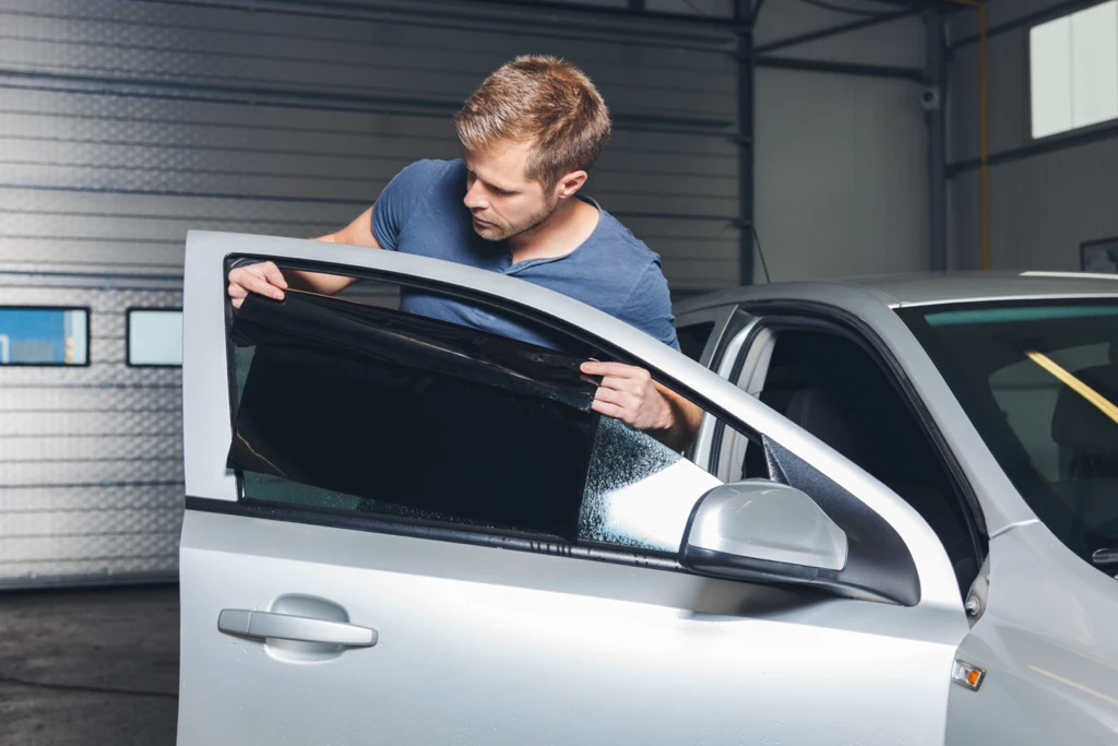 Homme installant une vitre teintée sur une voiture respectant les lois en vigueur au Québec.