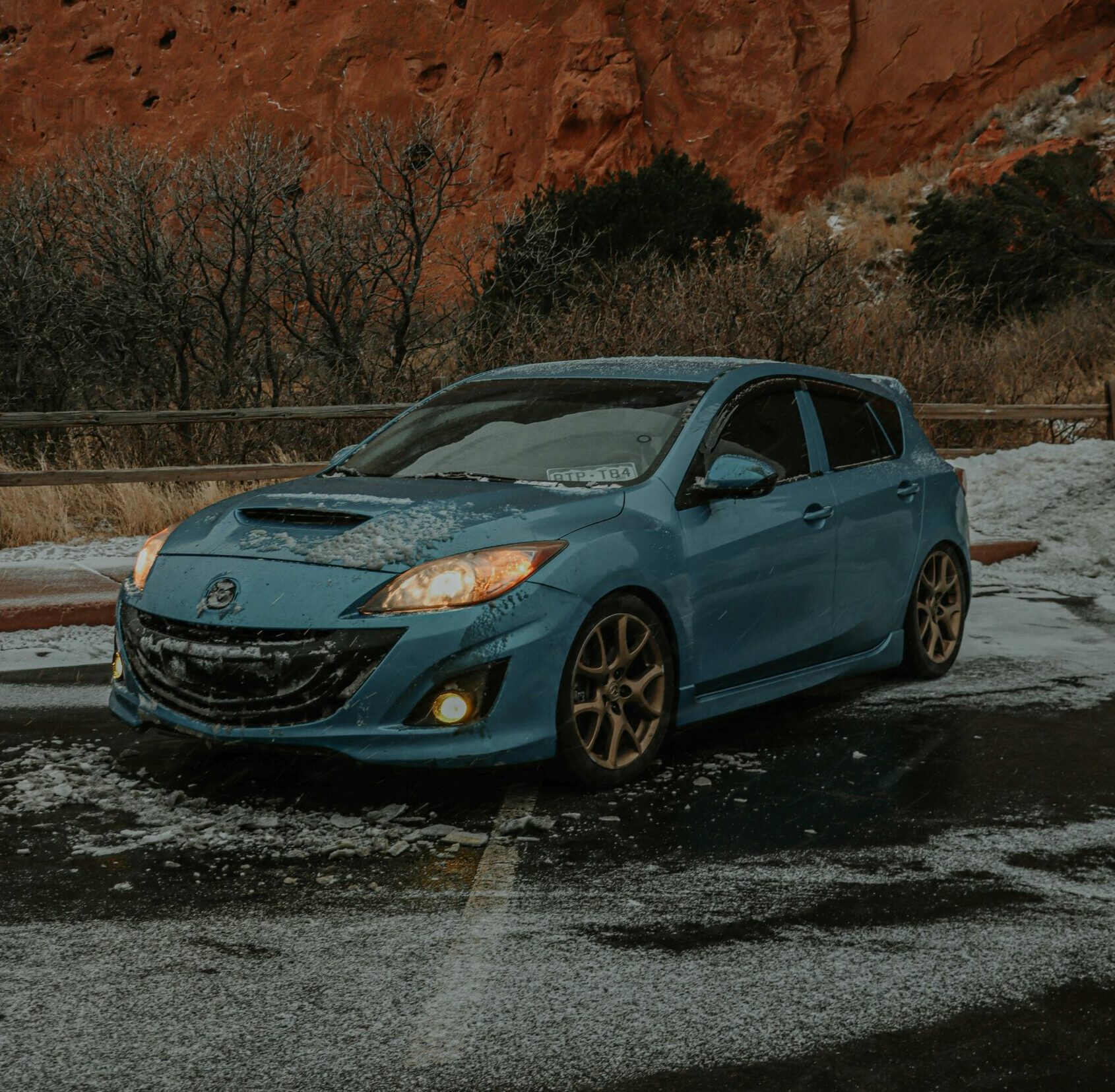 Voiture bleue sur route enneigée.